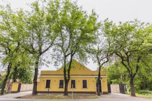 un edificio giallo con alberi di fronte di Vila Guliver a Palić