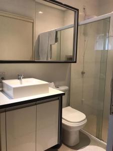 uma casa de banho com um lavatório, um WC e um espelho. em Apto - 30 min de BC em Brusque