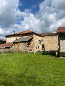 a large stone building with two chairs in a yard at La vieille forge in Boussan