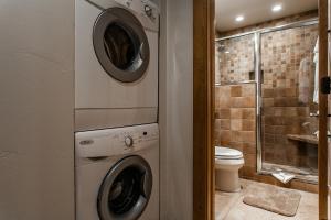 a bathroom with a washer and dryer next to a toilet at Snowmass Mountain by Snowmass Vacations in Snowmass Village
