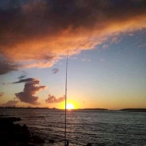 a sunset over a body of water with a pole at Araucaria in Oualidia