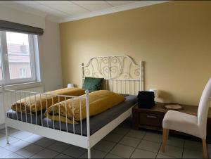 a bedroom with a bed and a chair and a window at Het Damhert in Kortenaken