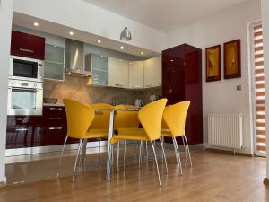 a kitchen with a table and yellow chairs in it at Kyra Luxury Penthouse in Sinaia