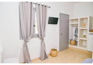 Habitación con ventana con cortinas y TV. en Avgerinos Deluxe Rooms, en Paliochori