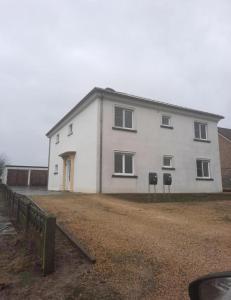 Une grande maison blanche avec deux panneaux devant elle dans l'établissement Het Damhert, à Kortenaken