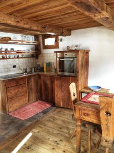 una cocina con armarios de madera, mesa y fregadero en Piccolo e accogliente rascard CIR 0060 en Champoluc