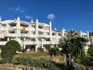 a large white building with palm trees in front of it at Jardines de Calahonda in Mijas Costa