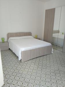 a bedroom with a large white bed and a carpet at Olga’s house in Cariati