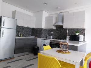 a kitchen with a white refrigerator and a table with yellow chairs at Harmony Appartement 13 in Tunis