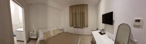 a white room with a television and chairs in it at A casa di Maghi in Olbia