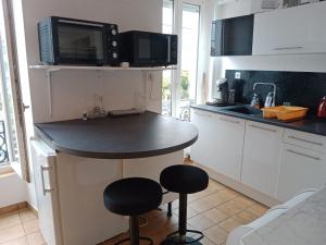 a kitchen with a counter with stools and a microwave at Vitré centre Ville bel appartement a découvrir in Vitré
