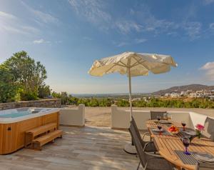 um pátio com uma banheira de hidromassagem e uma mesa com um guarda-sol em Villa Di Sergio em Glinado Naxos