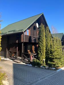 a log cabin with a green roof and some trees at Chalet Flery in Migovo