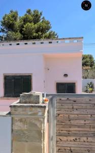 une maison rose avec une clôture devant elle dans l'établissement Villa Alma, à Collepasso