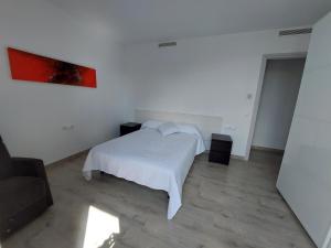 1 dormitorio con 1 cama blanca y una pintura roja en la pared en Àtic al centre de Girona, en Girona