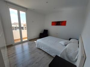 a white bedroom with a bed and a large window at Àtic al centre de Girona in Girona