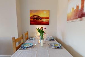a white table with plates and flowers on it at Contemporary 2 Bed Apartment With Private Garden in Maidstone