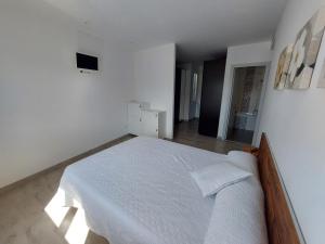 a white bedroom with a large bed with white sheets at Àtic al centre de Girona in Girona