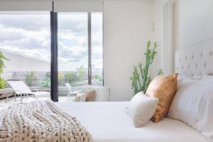 a bedroom with a white bed and a large window at Architectural Home, Pool Oasis/ Steps from Trendy Chapel St. in Melbourne
