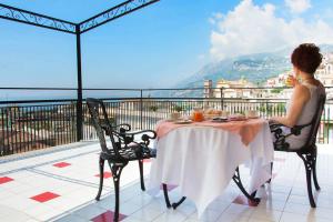 een vrouw aan een tafel op een balkon bij Sunrise Guest House in Maiori