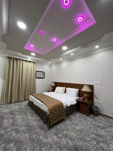 a bedroom with a large bed with purple lights on the ceiling at سويت ان العلا للشقق المفروشة الخاصة Sweet In alula Apartments and organizing tours in AlUla
