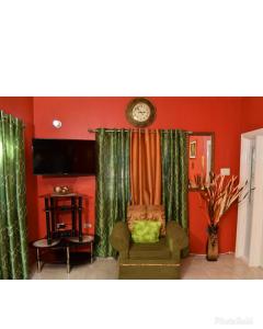Caribbean estate deluxe 2 في بورتمور: غرفة معيشة بها كرسي وساعة على الحائط