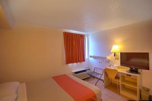 a hotel room with a bed and a desk with a television at Motel 6-Council Bluffs, IA - Omaha East in Council Bluffs
