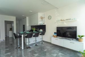 a kitchen with a table and stools and a tv at Relax Beach Apartman in Fonyód