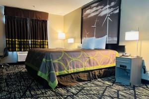 ein Hotelzimmer mit einem großen Bett und einem Schreibtisch in der Unterkunft Super 8 by Wyndham Pratt in Pratt