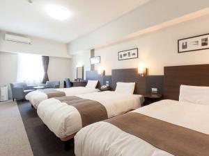 a hotel room with four beds in a row at Comfort Hotel Central International Airport in Tokoname