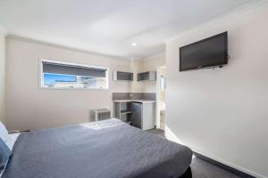 een slaapkamer met een bed en een flatscreen-tv bij Quality Inn Napier in Napier