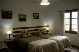 Un dormitorio con dos camas y una ventana. en Estancia La Angostura, en Las Horquetas