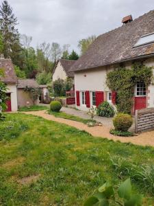 een wit huis met rode deuren en een tuin bij Le Calme à la source in Bréchamps