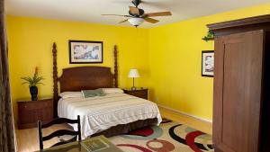 a yellow bedroom with a bed and a ceiling fan at Volcano Forest Inn in Volcano
