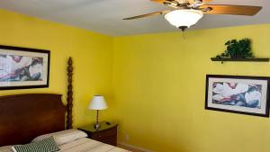 a bedroom with yellow walls and a bed and a ceiling fan at Volcano Forest Inn in Volcano