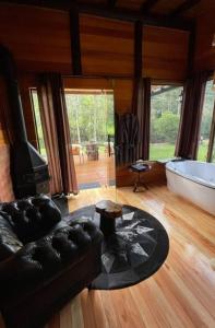 a living room with a tub and a black leather couch at Sentiero Cabanas Boutique in Urubici