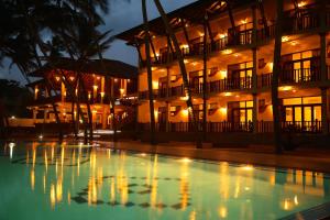 a building with a pool in front of it at night at Whispering Palms Hotel in Bentota