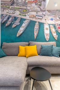 a couch with yellow pillows and a mural of boats at Casa Costabella in Split
