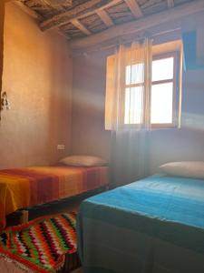 een slaapkamer met 2 bedden en een raam bij Berberbayt lodge maison privé in Tinerhir