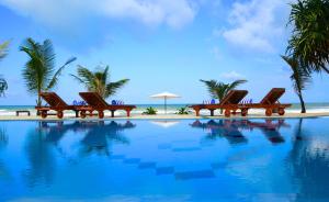 un grupo de sillas sentadas junto a una piscina en Whispering Palms Hotel, en Bentota