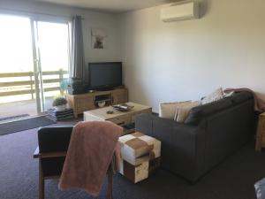 uma sala de estar com um sofá e uma televisão em Aratahi Cottages em Carterton