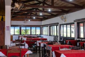 a restaurant with red tables and chairs and windows at Hotel Marina Clube de Pesca in Cananéia