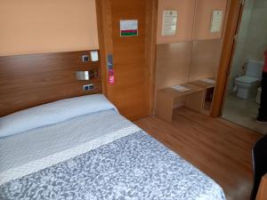 een kleine slaapkamer met een bed en een toilet bij Olimpia Hoteles in Totana