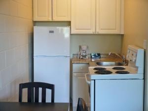 a kitchen with a white refrigerator and a stove at Westgate Inn in Portage La Prairie