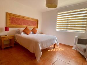 a bedroom with a bed and a chair and a window at La Casa de la Glorieta in Guanajuato