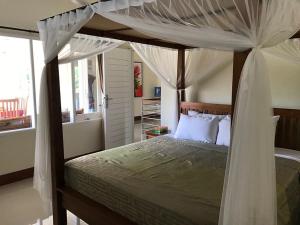 a bedroom with a canopy bed and a window at Bali Breeze Bungalows in Ubud