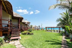 a house with a grass yard next to the ocean at Villa with ocean view, pool, restaurant and rooftop in Isla Mujeres