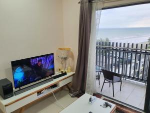 een woonkamer met een televisie en een balkon met uitzicht op de oceaan bij Swiss Garden Resort Residence, studio, sea & pool view, high level unit in Kuantan
