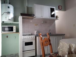 a kitchen with white appliances and a table with a chair at San Cayetano Departamento por dia con cochera gratis in Bahía Blanca