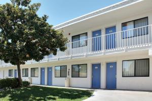 ein Gebäude mit blauen Türen und einem Baum in der Unterkunft Motel 6-Atascadero, CA in Atascadero